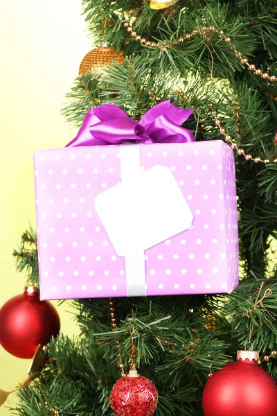 Regalo en el árbol de Navidad sobre fondo de color — Foto de Stock