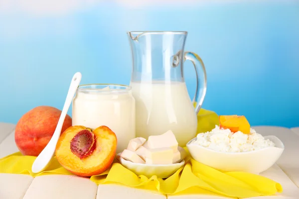 Frische Milchprodukte mit Pfirsichen auf Holztisch vor natürlichem Hintergrund — Stockfoto
