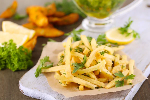 Patatine fritte su carta da lucido su tavola di legno — Foto Stock