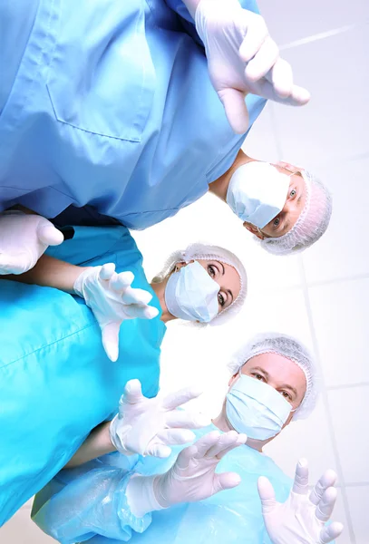 Vista de baixo de cirurgiões em desgaste de trabalho de proteção durante a operação — Fotografia de Stock