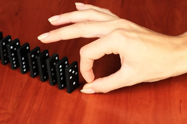 Mano spingendo domino su sfondo di legno — Foto Stock