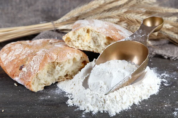 The wholemeal flour in scoop on wooden table on sackcloth background — Stock Photo, Image