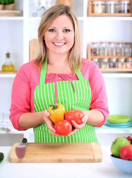 Feliz mulher sorridente na cozinha segurando legumes frescos em suas mãos — Fotografia de Stock