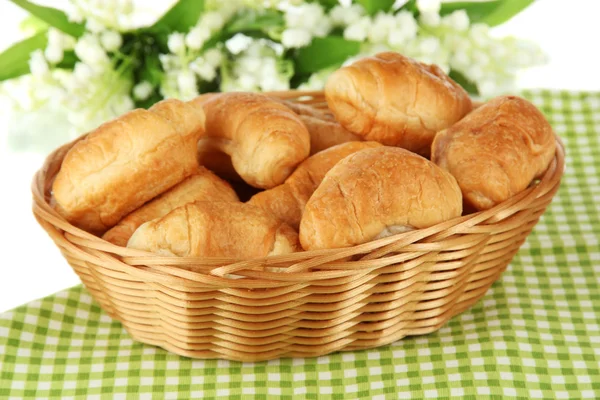 Läckra croissanter i flätade korgen på bordet på vit bakgrund — Stockfoto