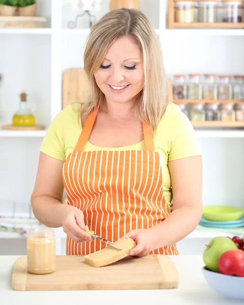Glücklich lächelnde Frau in der Küche bereitet Sandwich zu — Stockfoto