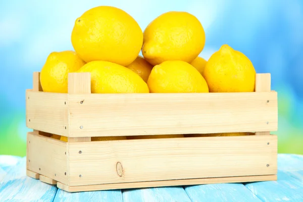 Ripe lemons in wooden box on table on bright background — Stock Photo, Image