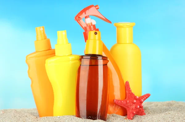 Botellas con crema bronceadora, sobre fondo azul — Foto de Stock