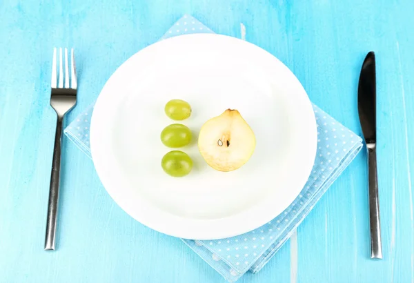 Small portion of food on big plate on wooden table close-up — Stock Photo, Image