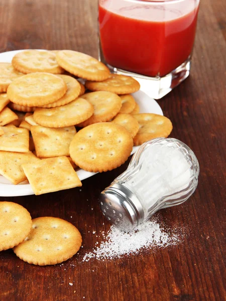 Delicious crackers with salt and tomato juice on wooden background — Stock Photo, Image