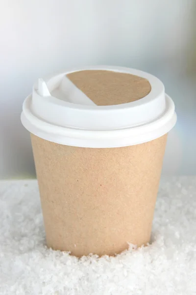 Varm dryck i papper kopp och snö på ljus bakgrund — Stockfoto