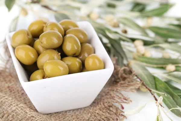 Olives in bowl with branch on sackcloth close up — Stock Photo, Image