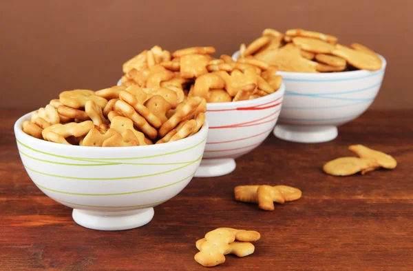 Výborné sušenky v miskách na dřevěný stůl na hnědé pozadí — Stock fotografie