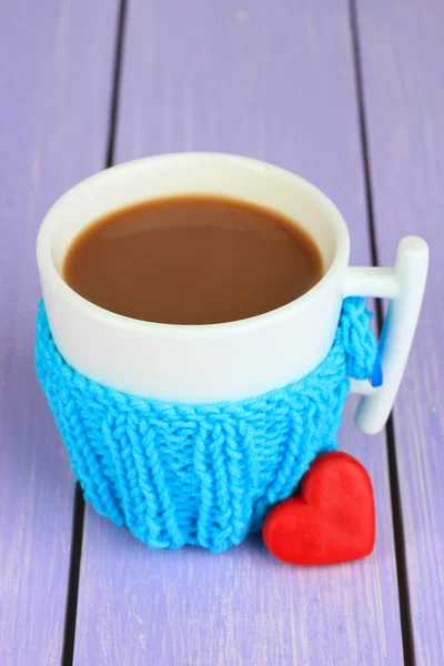 Cup with knitted thing on it on wooden table close up — Stock Photo, Image