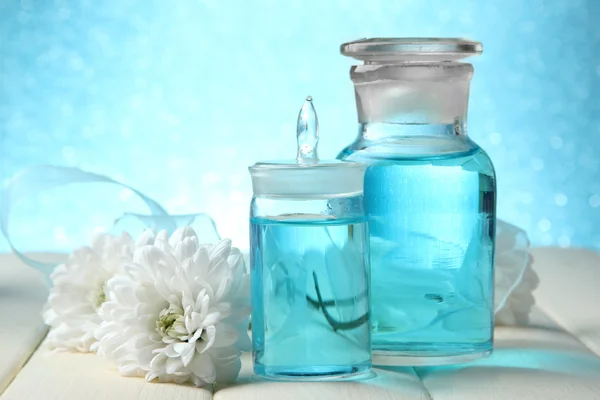 Bouteilles en verre avec essence de couleur, sur table en bois, sur fond bleu — Photo