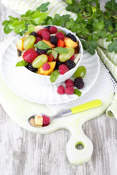 Ahşap masa arka plan üzerinde kase meyve salatası — Stok fotoğraf