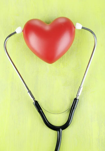 Stethoscope and heart on wooden table close-up — Stock Photo, Image