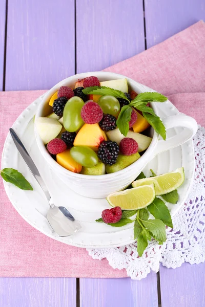 Insalata di frutta in tazza su tovagliolo su tavolo di legno — Foto Stock