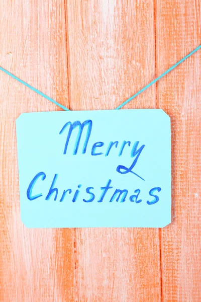 Cartello con le parole Buon Natale su sfondo tavolo di legno arancione primo piano — Foto Stock