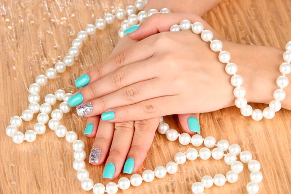 Mains de femme avec manucure tenant des perles — Photo
