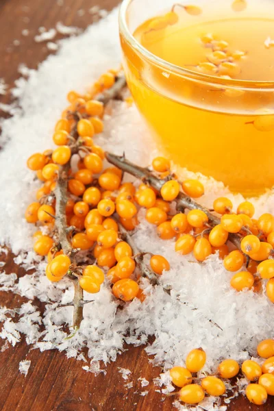 Branches of sea buckthorn with tea and snow on wooden background — Stock Photo, Image