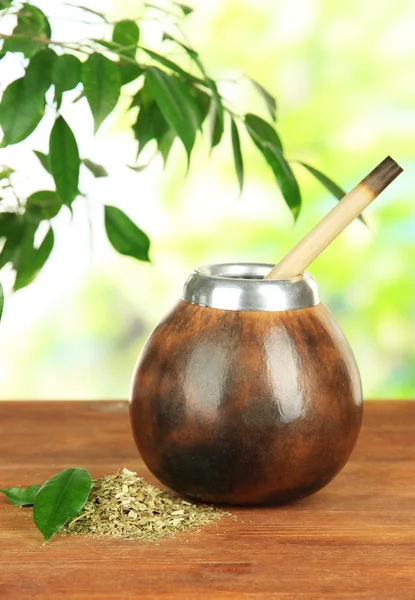 Kalebas en bombilla met yerba mate op houten tafel, op natuurlijke achtergrond — Stockfoto