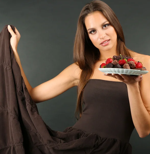 Девушка с шоколадными конфетами на тарелке — стоковое фото