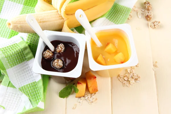 Smakelijke crème desserts met stukken van vers fruit, cookies en vlokken, op een houten achtergrond kleur — Stockfoto