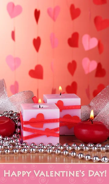 Kaarsen voor dag van de Valentijnskaart op houten tafel op rode achtergrond — Stockfoto