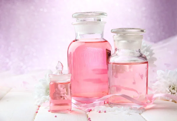 Bouteilles en verre avec essence de couleur, sur fond rose — Photo