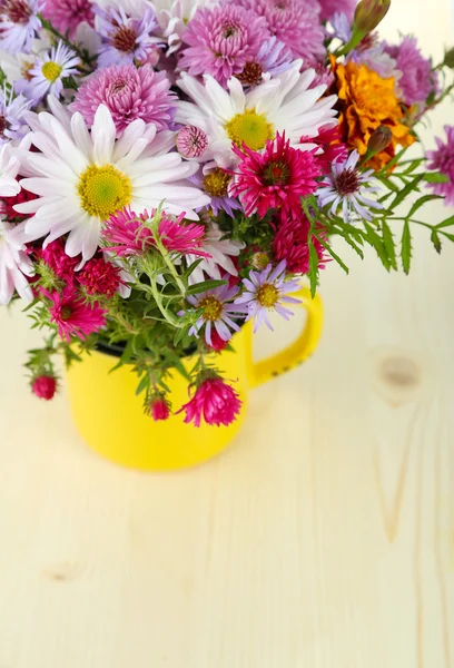 Fleurs sauvages en tasse sur table en bois — Photo