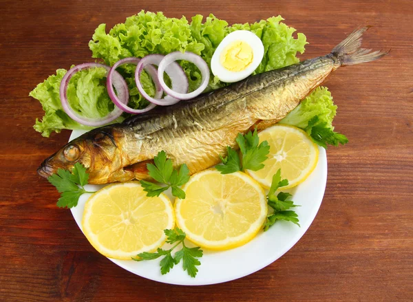 Uzené ryby na talíři na dřevěném stole — Stock fotografie