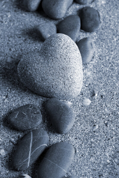 Grey stone in shape of heart, on sand background