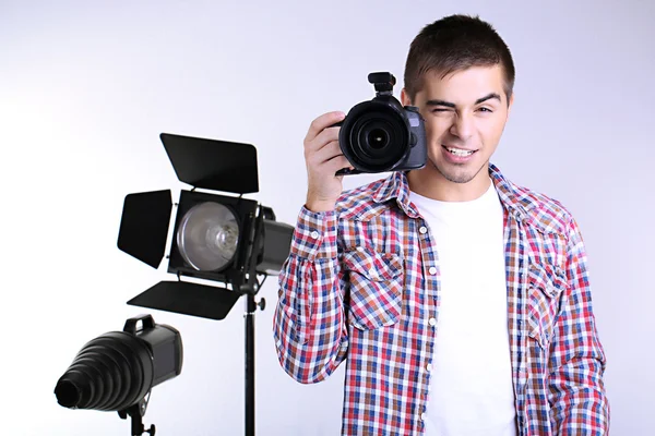 Beau photographe avec appareil photo, sur fond de studio photo — Photo