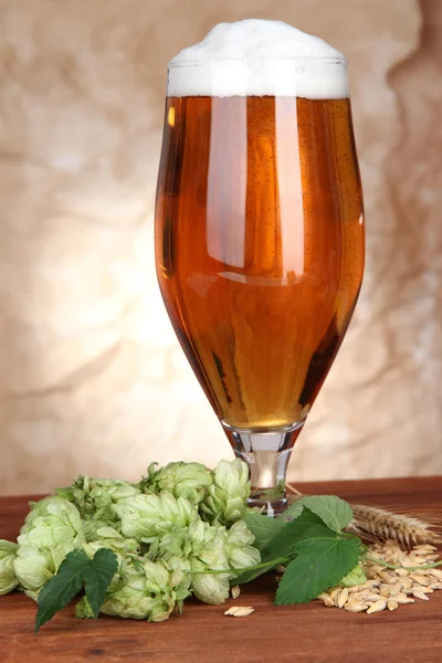 Glass of beer and hops, on wooden table — Stock Photo, Image