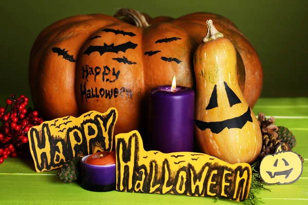 Composizione per Halloween con zucche e candele su tavolo in legno su sfondo a colori — Foto Stock