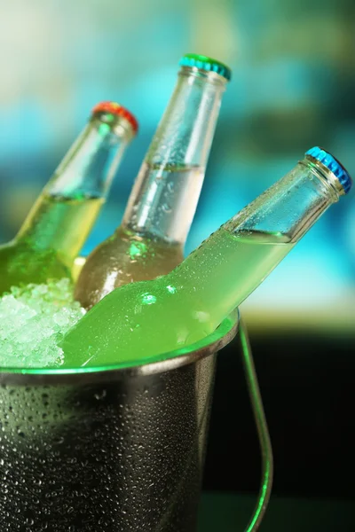 Bevande in bottiglia in secchio di ghiaccio su sfondo luminoso — Foto Stock