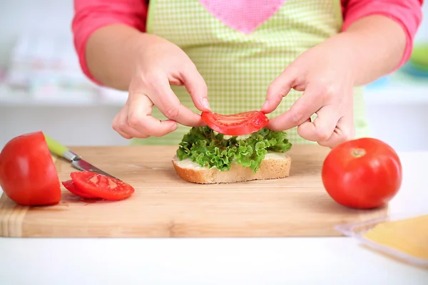 Glada leende kvinna i köket förbereder sandwich, närbild — Stockfoto