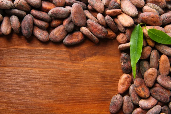 Какао бобы с листьями на деревянном фоне — стоковое фото