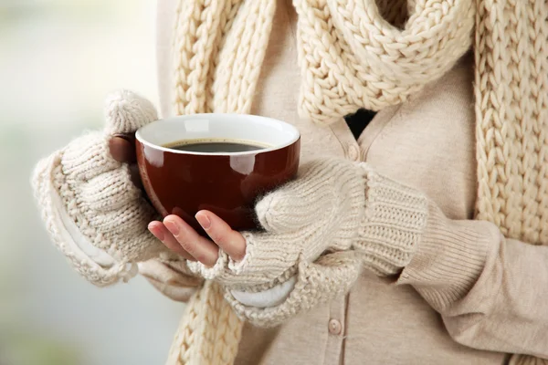 Vrouwelijke handen met warme dranken, op lichte achtergrond — Stockfoto