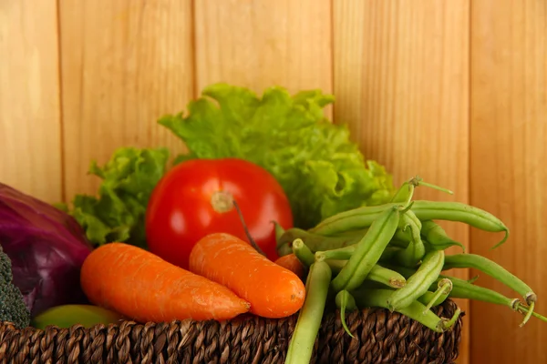 Different vegetables in basket on wooden background — Stock Photo, Image