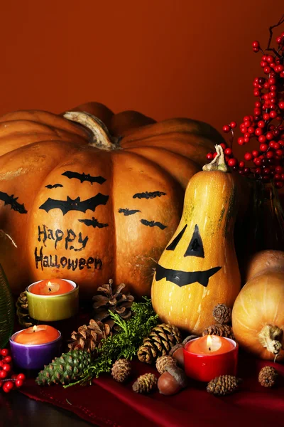 Samenstelling voor halloween met pompoenen en kaarsen op oranje achtergrond — Stockfoto