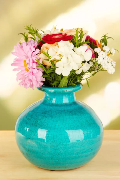 Krásné světlé kytice v barevné vázy, na dřevěný stůl, na světlé pozadí — Stock fotografie