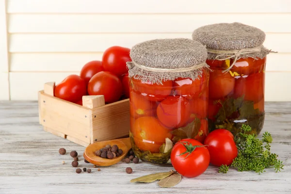 Вкусные консервированные и свежие помидоры на деревянном столе — стоковое фото