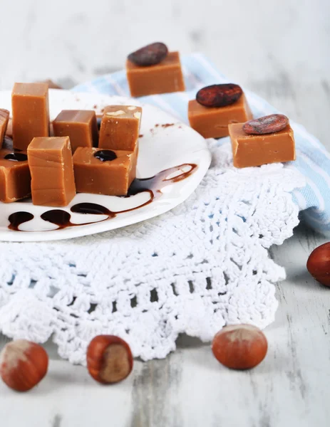 Many toffee on plate on napkins on wooden table — Stock Photo, Image