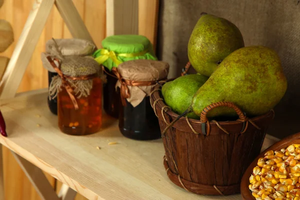 Potten jam met peren in mand op plank op rouwgewaad achtergrond — Stockfoto