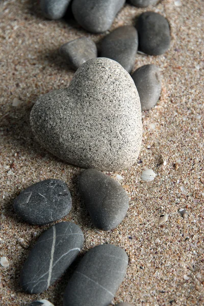 Pedra cinzenta em forma de coração, sobre fundo de areia — Fotografia de Stock