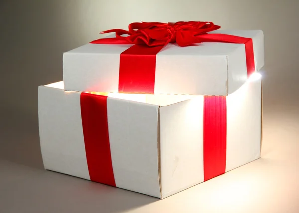 Geschenkbox mit hellem Licht auf grauem Hintergrund — Stockfoto