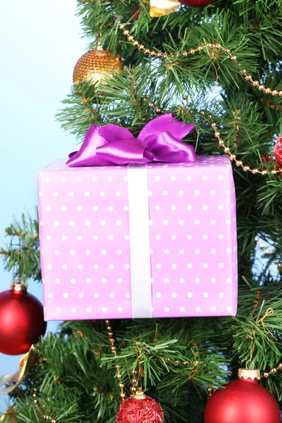 Regalo en el árbol de Navidad sobre fondo de color — Foto de Stock