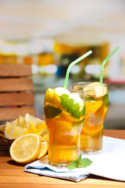 Té helado con limón y menta en la mesa de madera, al aire libre —  Fotos de Stock