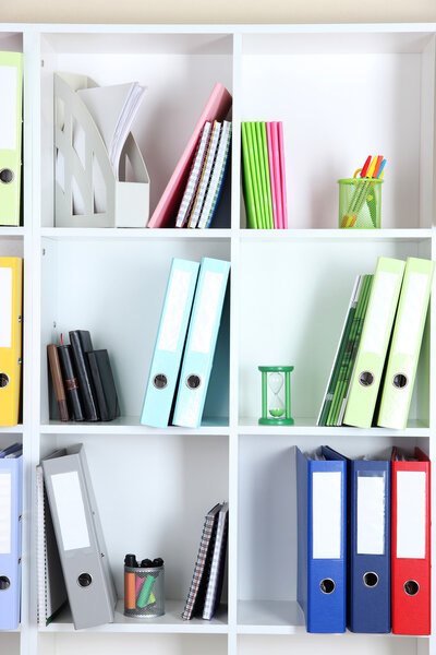 White office shelves with folders and different stationery, close up